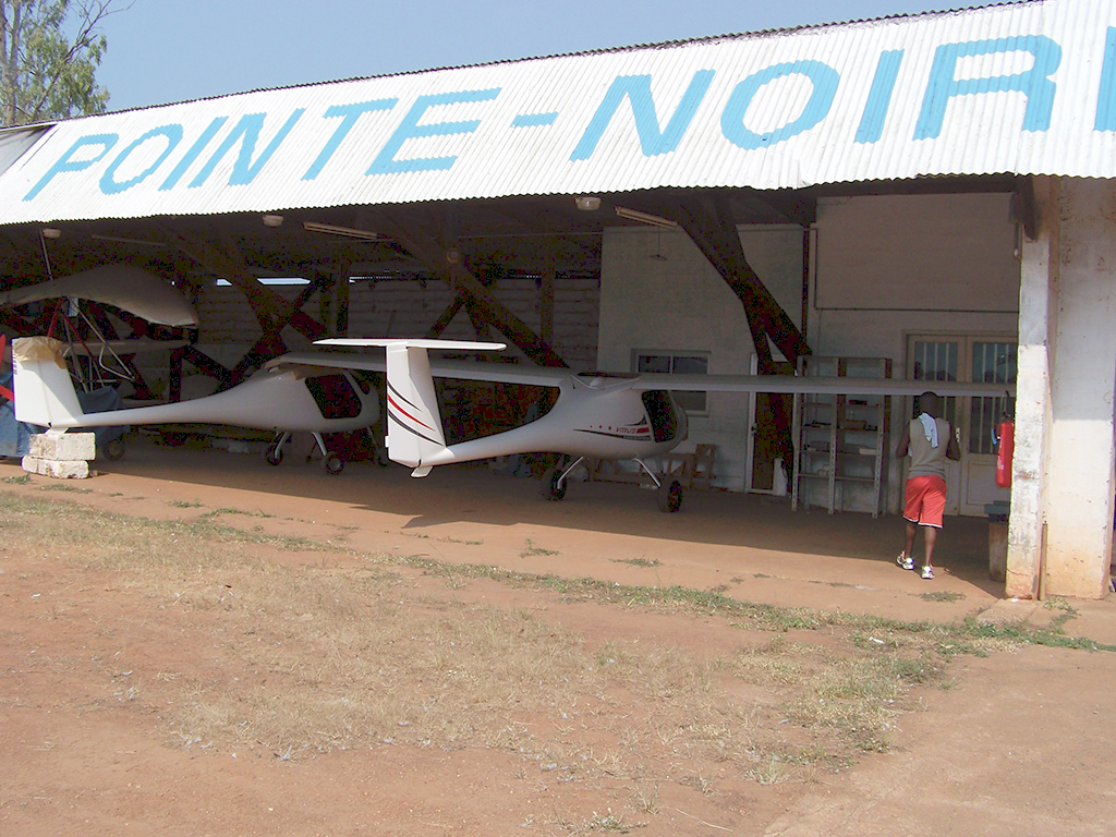 Un petit avion blanc garé devant un bâtiment, mettant en valeur son design élégant sur fond de structure.