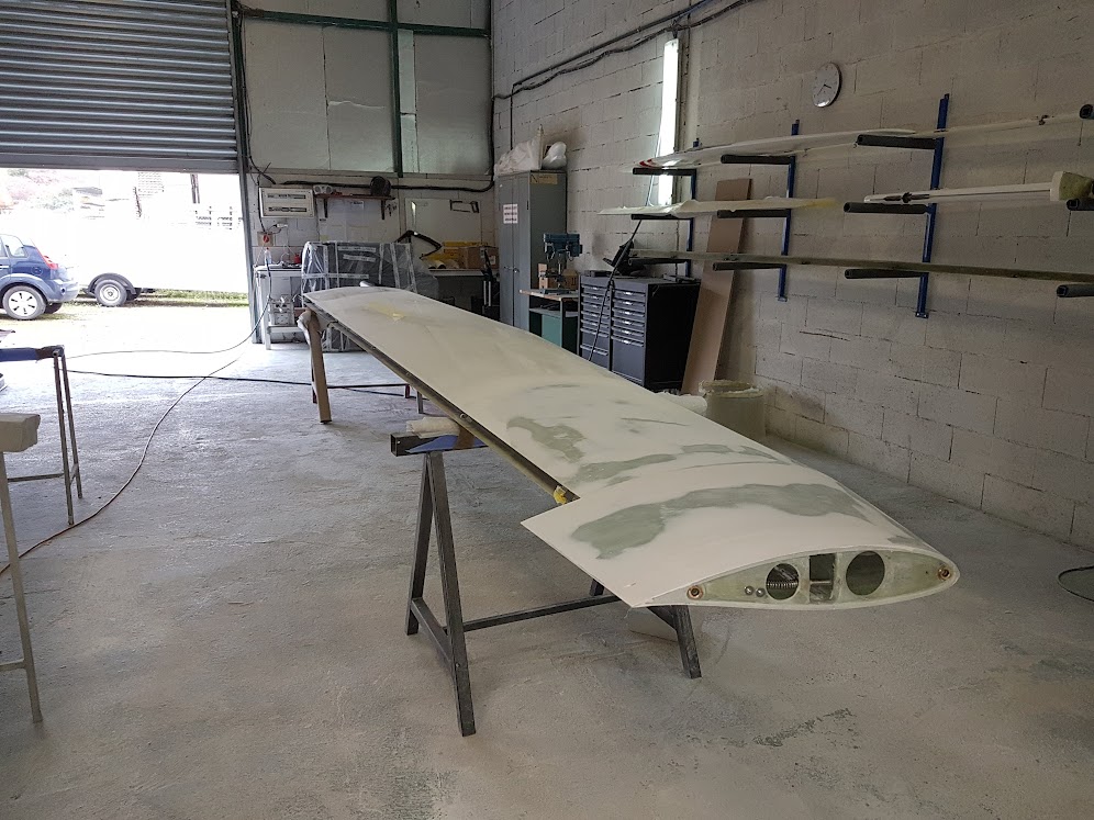 Dans un atelier, une planche de surf est en cours de fabrication, mettant en valeur les outils et les matériaux utilisés dans le processus de construction.