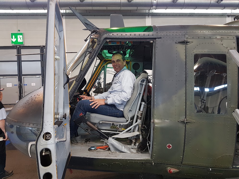 Un homme assis dans le cockpit d'un hélicoptère, concentré sur les commandes et les instruments devant lui.