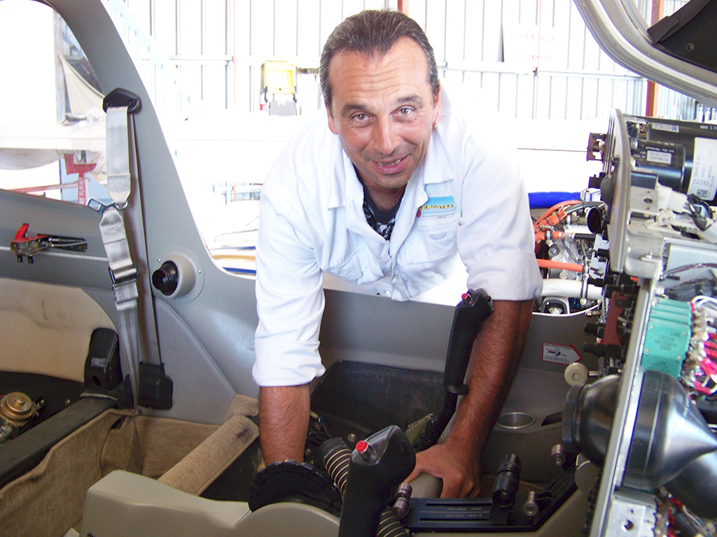 Un homme aux commandes d'un hélicoptère depuis le cockpit, entouré de divers instruments de vol et commandes.