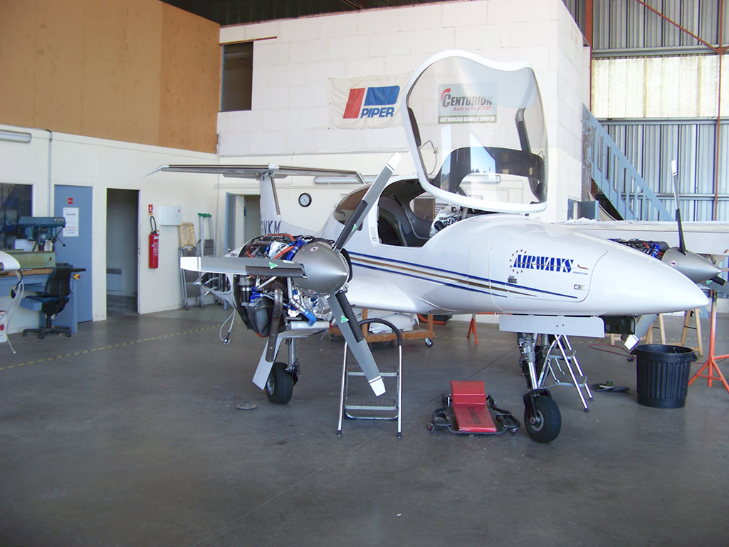 Un petit avion blanc est stationné devant un bâtiment, soulignant sa présence dans le paysage aéronautique.