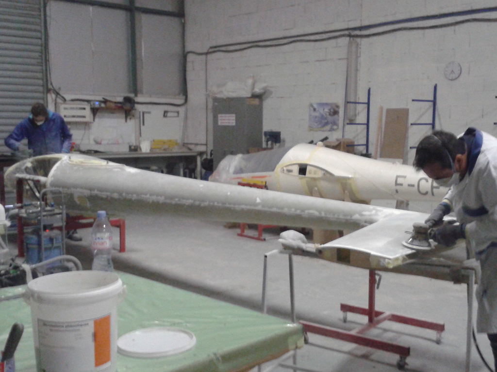 Une planche de surf est en cours d'assemblage dans un atelier, mettant en valeur le savoir-faire et les outils nécessaires à sa fabrication.